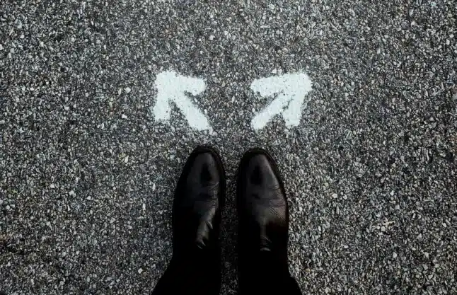 Shoes and 2 arrows pointing in 2 different directions, showing the GHG Protocol’s Scope 2 accounting method choices.