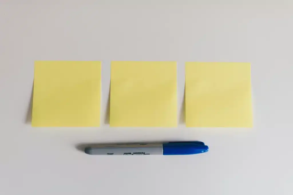 Des feuilles de blocs-notes et un marqueur symbolisant les étapes pour réaliser un bilan carbone
