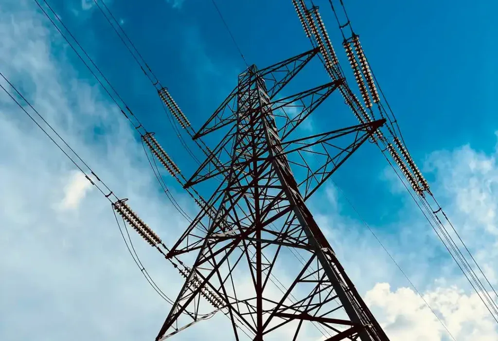 High-voltage electricity transmission tower against a blue sky