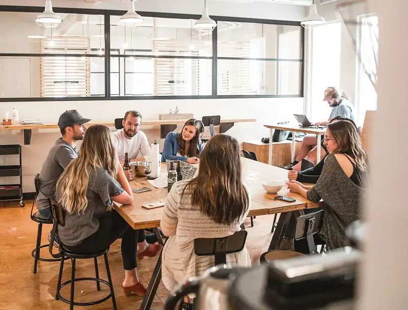 Group of professionals discussing corporate strategy around a wooden table in a bright office.